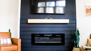 A modern living room with a flat-screen TV mounted above a fireplace. - Trail Chaser Moab, UT (Moab)