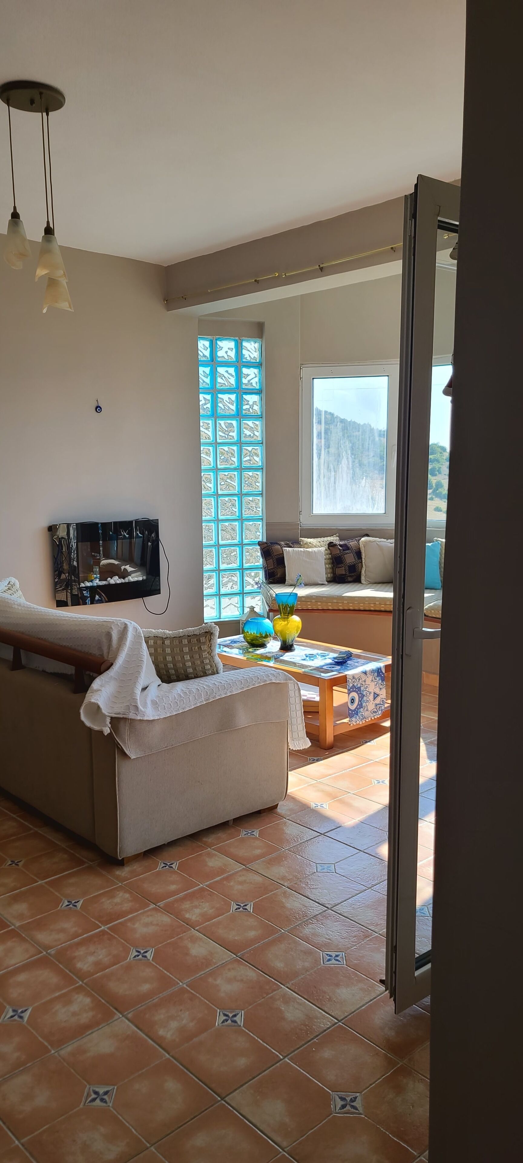 A living room with a sofa, a coffee table, and a view of a mountainous landscape through a window.