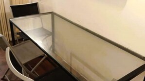 A glass-top table with chairs, a white wall, and a radiator.