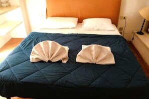 A bed with a dark blue quilt, two folded white towels, and an orange headboard. - Ponte Vecchio up to 4 (Firenze)