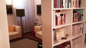 A living room with a sofa, a bookshelf, and a lamp.
