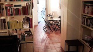 A room with a tiled floor, a dining table with chairs, and bookshelves filled with books.