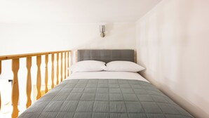 A bedroom with a bed, wooden railing, and a wall-mounted light fixture. - Native Apartments Nowowiejska 9 (Kraków)