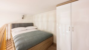 A bedroom with a bed, a wardrobe, and a small wall-mounted light. - Native Apartments Nowowiejska 9 (Kraków)