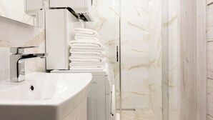 A modern bathroom with a white sink, a mirror, and a glass shower enclosure. - Native Apartments Nowowiejska 9 (Kraków)