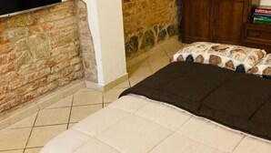 Une pièce avec un lit, un mur en pierre et une armoire en bois.