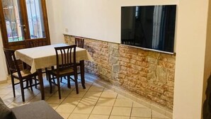 Un coin repas avec une table et des chaises, un mur en pierre et un téléviseur à écran plat fixé au mur.