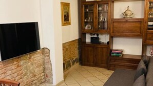 Un salon avec un mur en pierre, des meubles en bois, un téléviseur et un canapé.