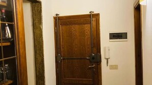 Une porte en bois avec une poignée et une serrure en métal, une petite prise électrique et un interrupteur sur le mur.