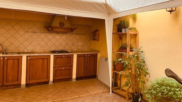 Une cuisine avec des meubles en bois, un dosseret carrelé et une structure blanche en forme de tente.