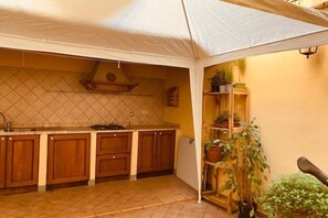 Una cocina con armarios de madera, salpicadero de azulejos y una estructura blanca similar a una tienda de campaña.