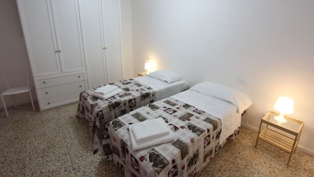 A bedroom with two beds, a wardrobe, and bedside lamps. - A Pochi Metri dal Duomo! (Firenze)