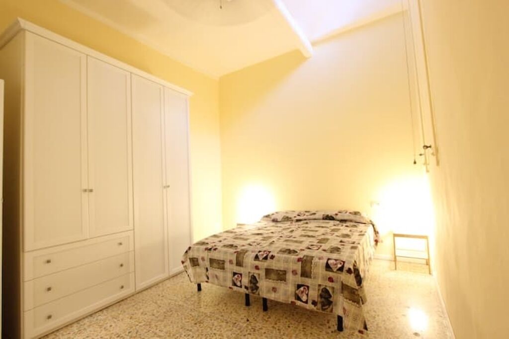 Un dormitori amb llit, armari i tauleta de nit.