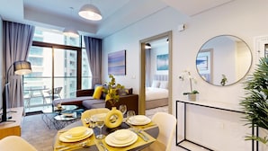 A modern hotel room with a dining area, a sofa, a large window, and a mirror. - Elegant 2 Bed| Business Bay | Central & Convenient - Aykon City Tower (Business Bay)