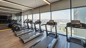 A gym with treadmills, ellipticals, and weights, large windows with a city view. - Elegant 2 Bed| Business Bay | Central & Convenient - Aykon City Tower (Business Bay)