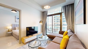 A modern hotel room with a large bed, a TV, a sofa, and a balcony with a view of high-rise buildings. - Elegant 2 Bed| Business Bay | Central & Convenient - Aykon City Tower (Business Bay)