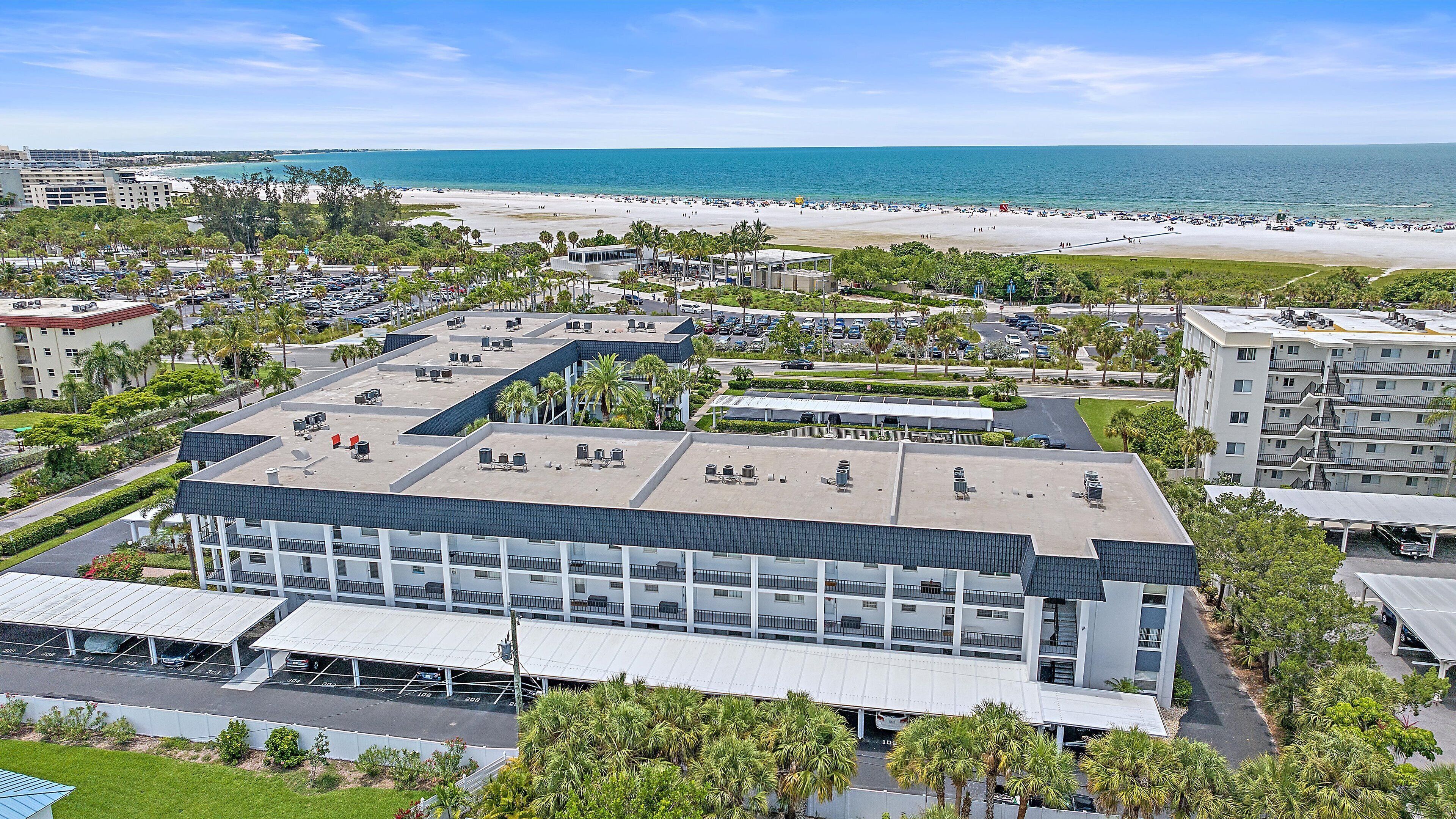 A hotel with a rooftop pool, a beach view, and a parking lot.