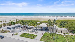 A beachfront hotel with a modern design, featuring a pool area, palm trees, and a view of the beach and ocean.
