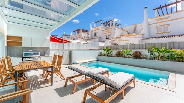 Un área de piscina exterior moderna con un conjunto de comedor y sillones de relax.