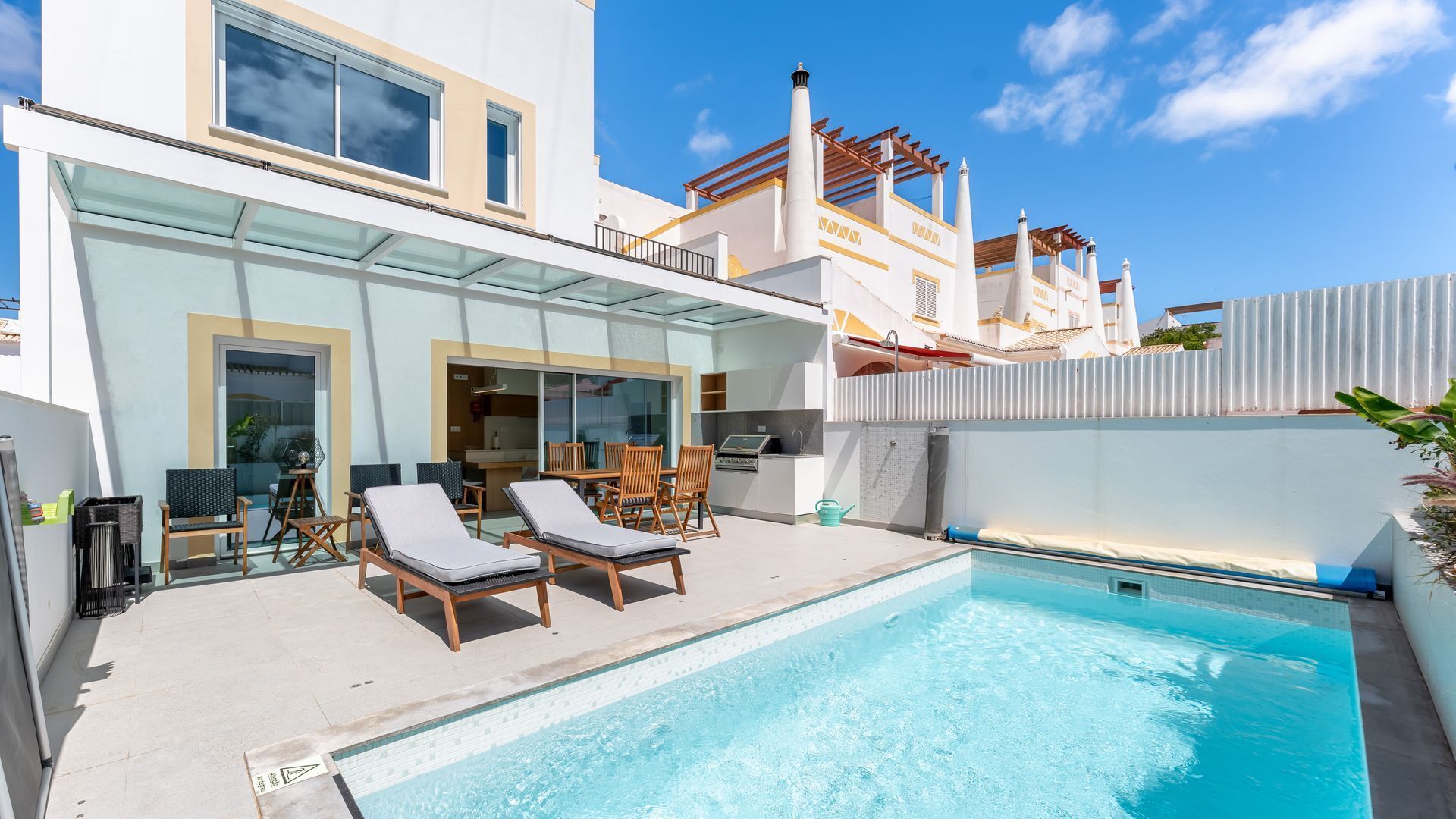 Een modern zwembadgedeelte met ligbedden, een glazen patio en een helderblauw zwembad.