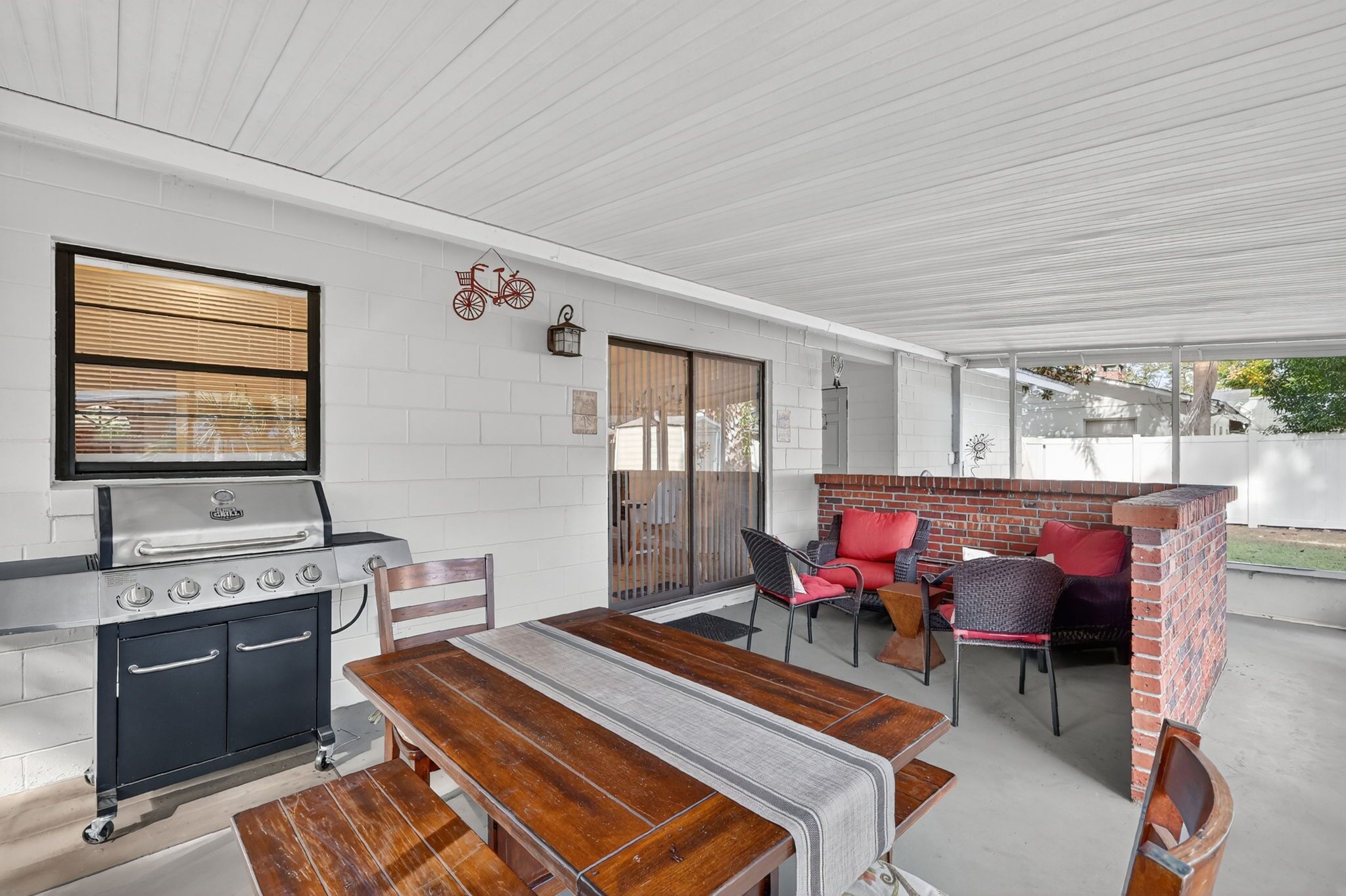 Une terrasse extérieure équipée d’un barbecue, d’une table à manger et de sièges.