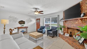 A living room with a sofa, armchairs, a coffee table, a fireplace, a TV, and a window with a view. - Cozy Stay in Ocala 3 Bedroom House, King Bed, Fenced, Peaceful & Pet Friendly  (Ocala)
