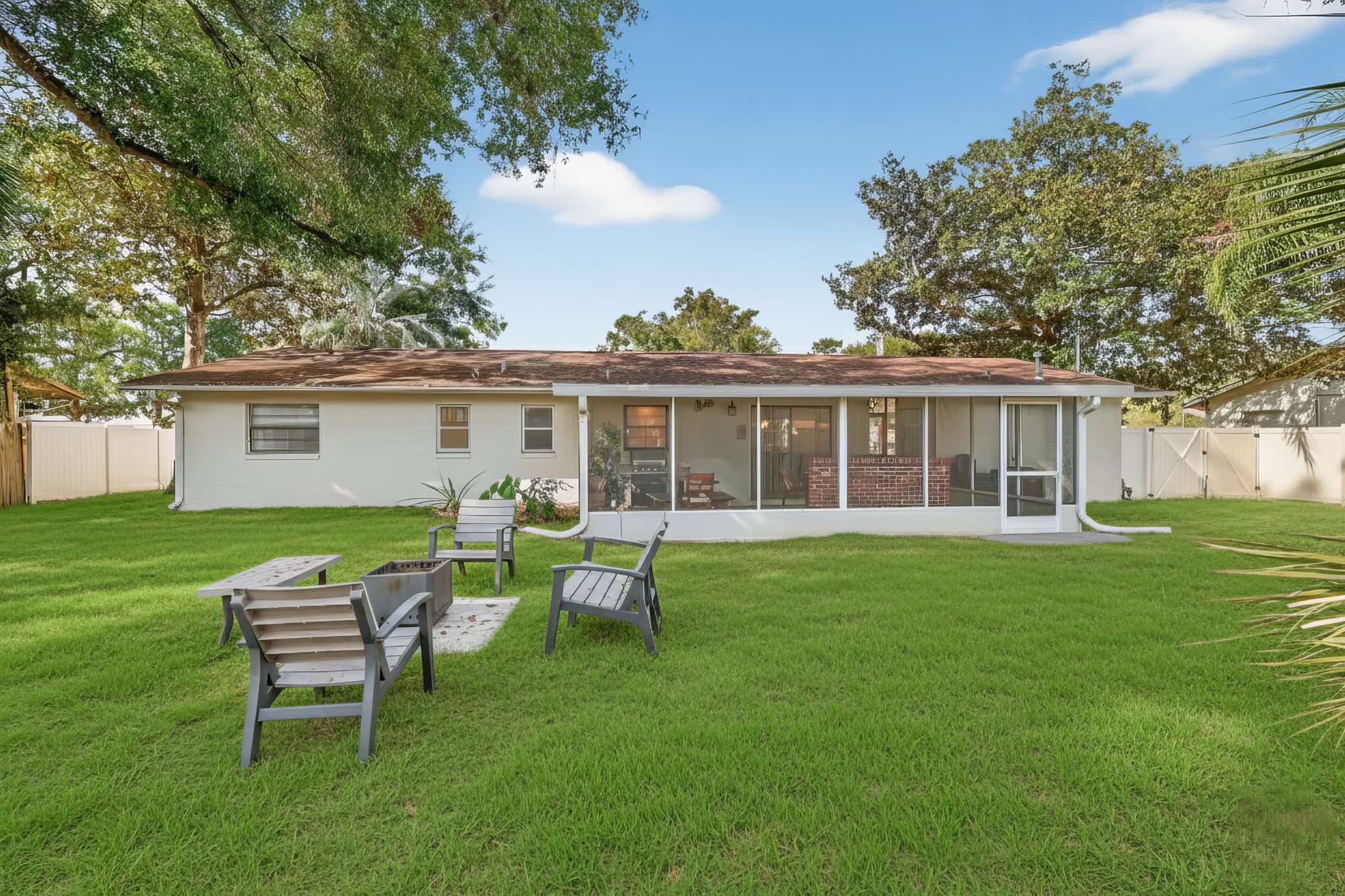 A single-story house with a covered patio, a lawn, and a fenced yard.