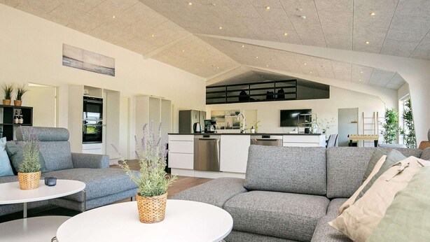 A modern living room with grey sofas, a white coffee table, and a kitchen area in the background. - 22 Person Holiday Home in Lokken-by Traum (Lokken)