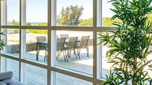 A sunroom with large windows overlooking a deck with outdoor furniture. - 22 Person Holiday Home in Lokken-by Traum (Lokken)