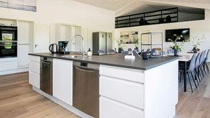 A modern kitchen with a central island, built-in appliances, and a dining area with chairs and a table. - 22 Person Holiday Home in Lokken-by Traum (Lokken)