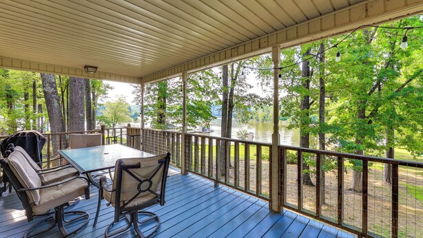 A covered deck with a table and chairs, overlooking a lake and trees. - Waterfront Wheeler Lake Home w/ Furnished Deck (Athens)