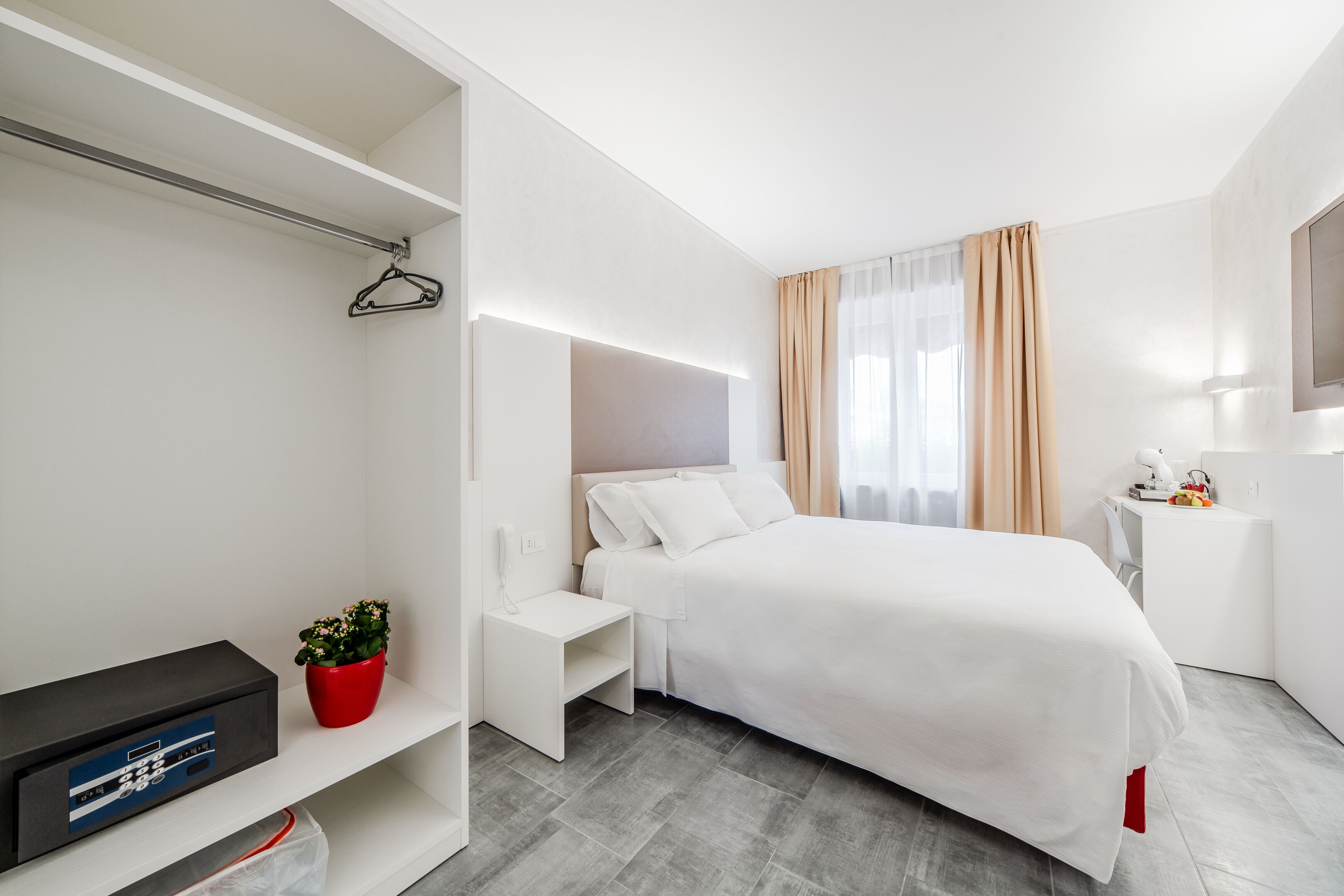 A modern hotel room with a bed, bedside table, and a TV stand.