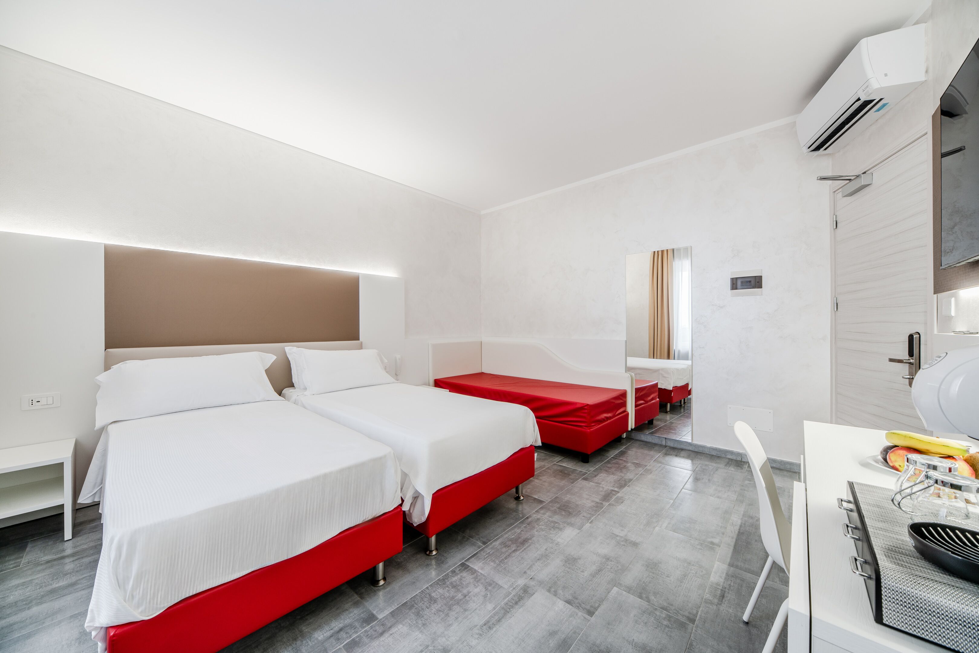 A hotel room with two beds, a desk, and a chair.