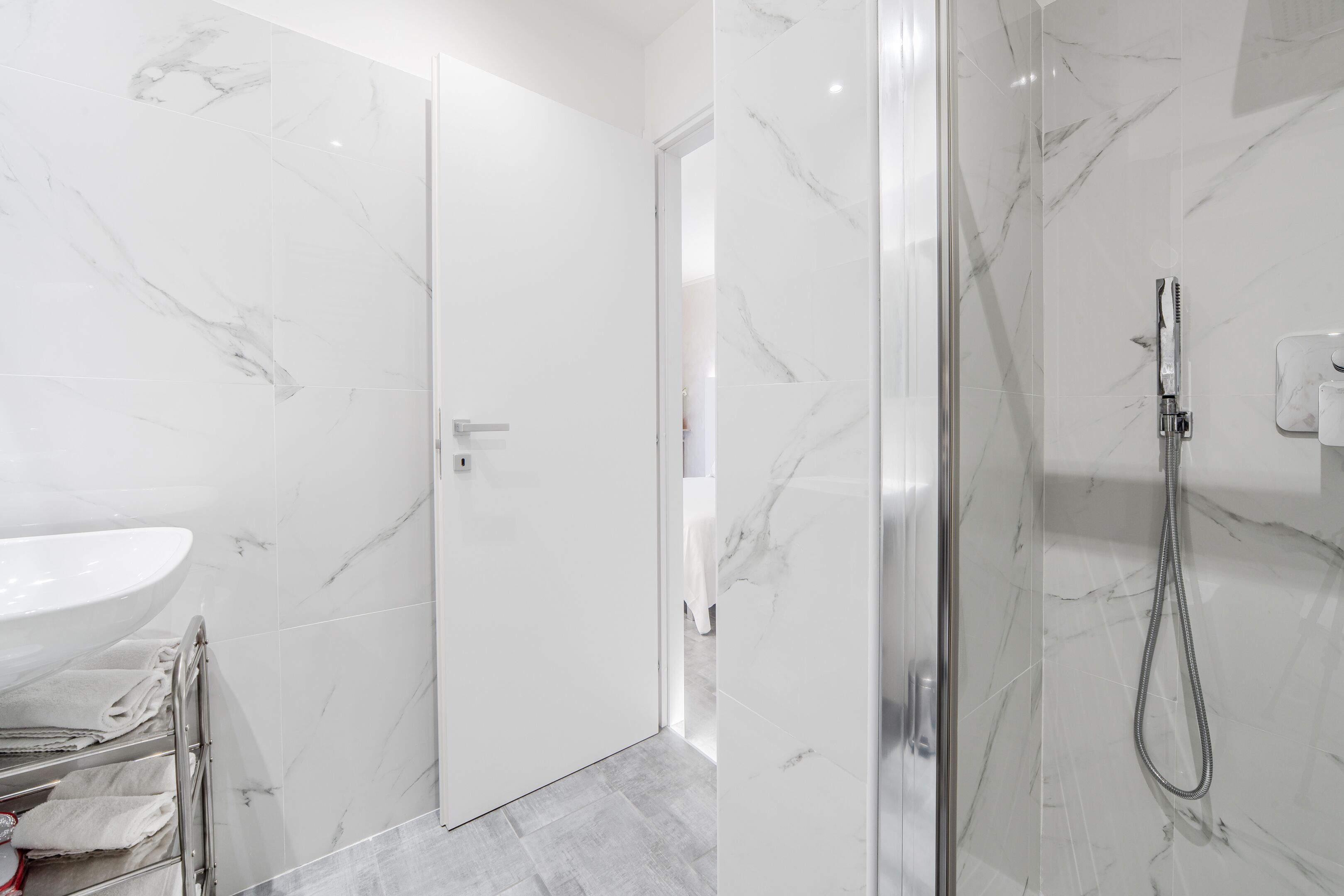 Une salle de bain moderne avec une douche en marbre, un lavabo et une porte en verre.