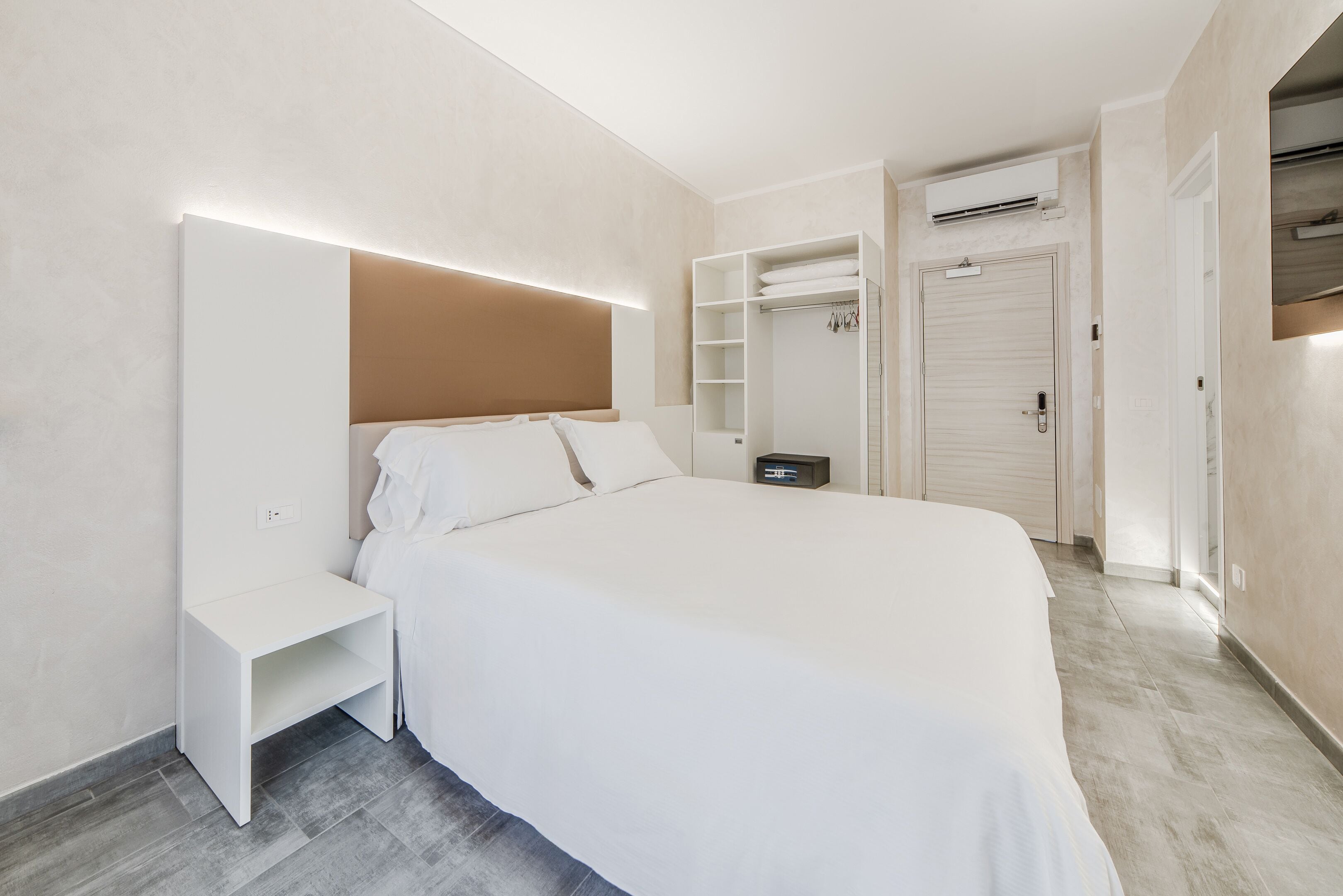 Ein modernes Schlafzimmer mit einem großen Bett, Nachttischen, einem Kleiderschrank und einer Klimaanlage.
