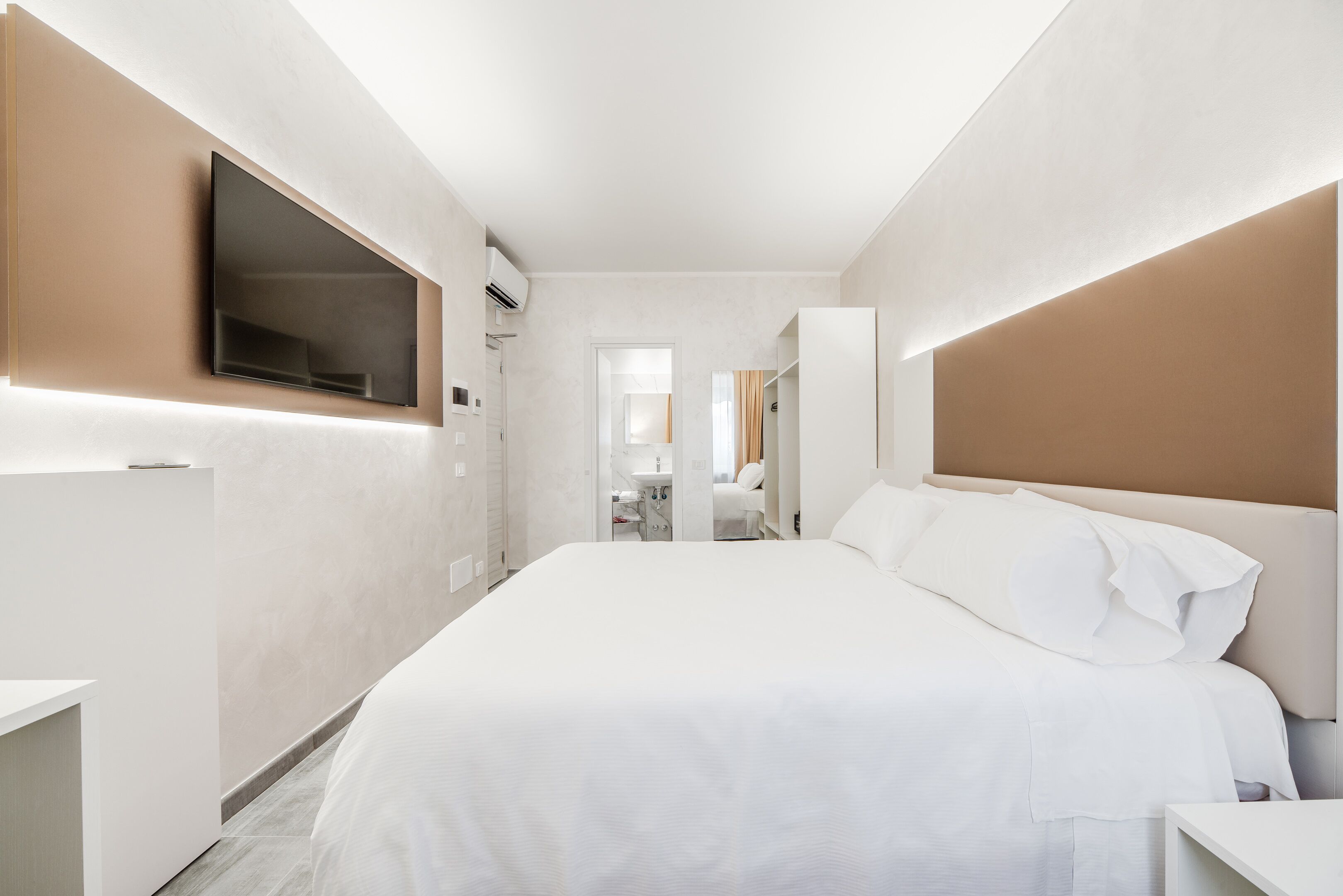 Una camera d'albergo moderna con un letto grande, una TV a schermo piatto montata a parete e un armadio a muro.