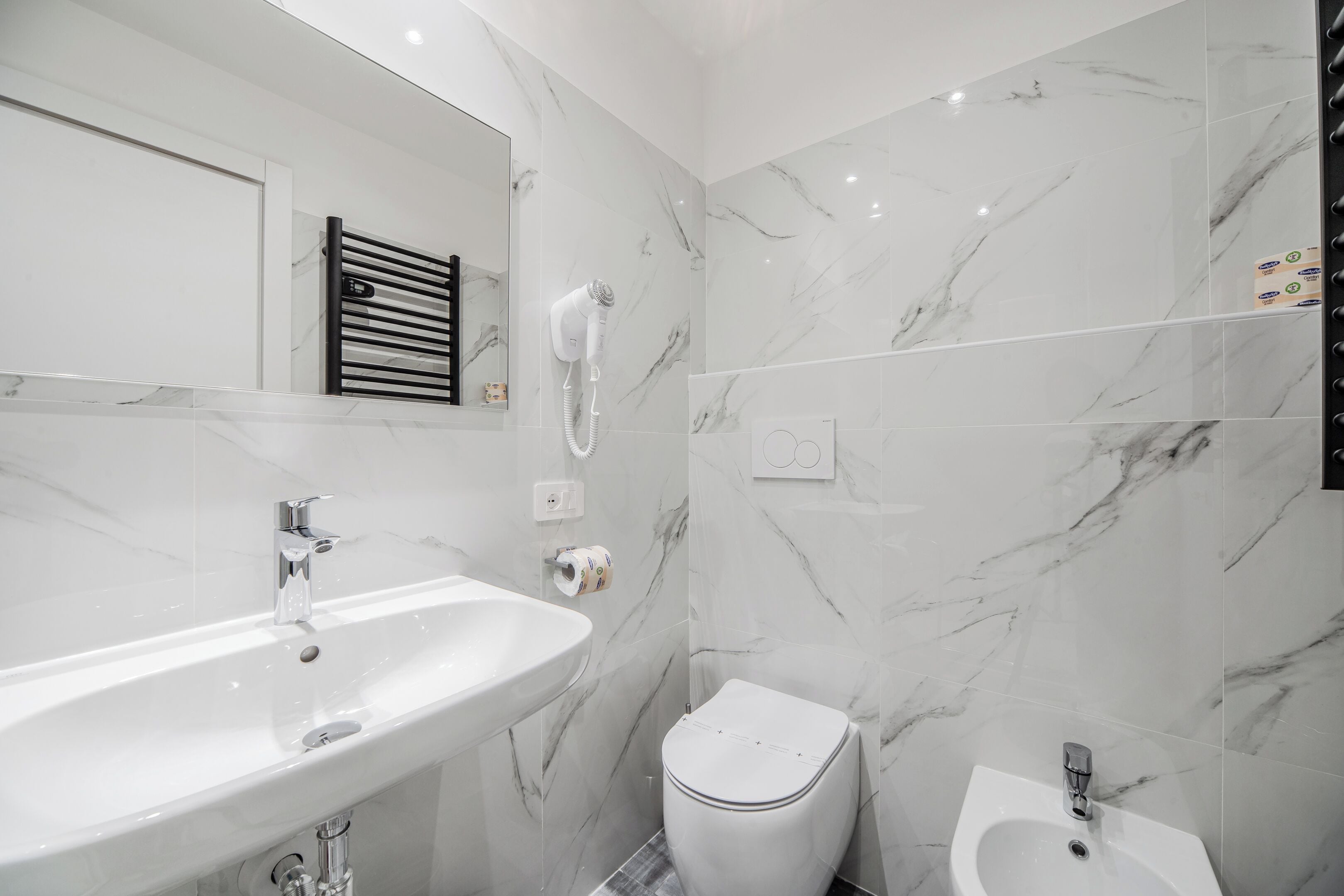 A modern bathroom with a white sink, a toilet, and a bidet.