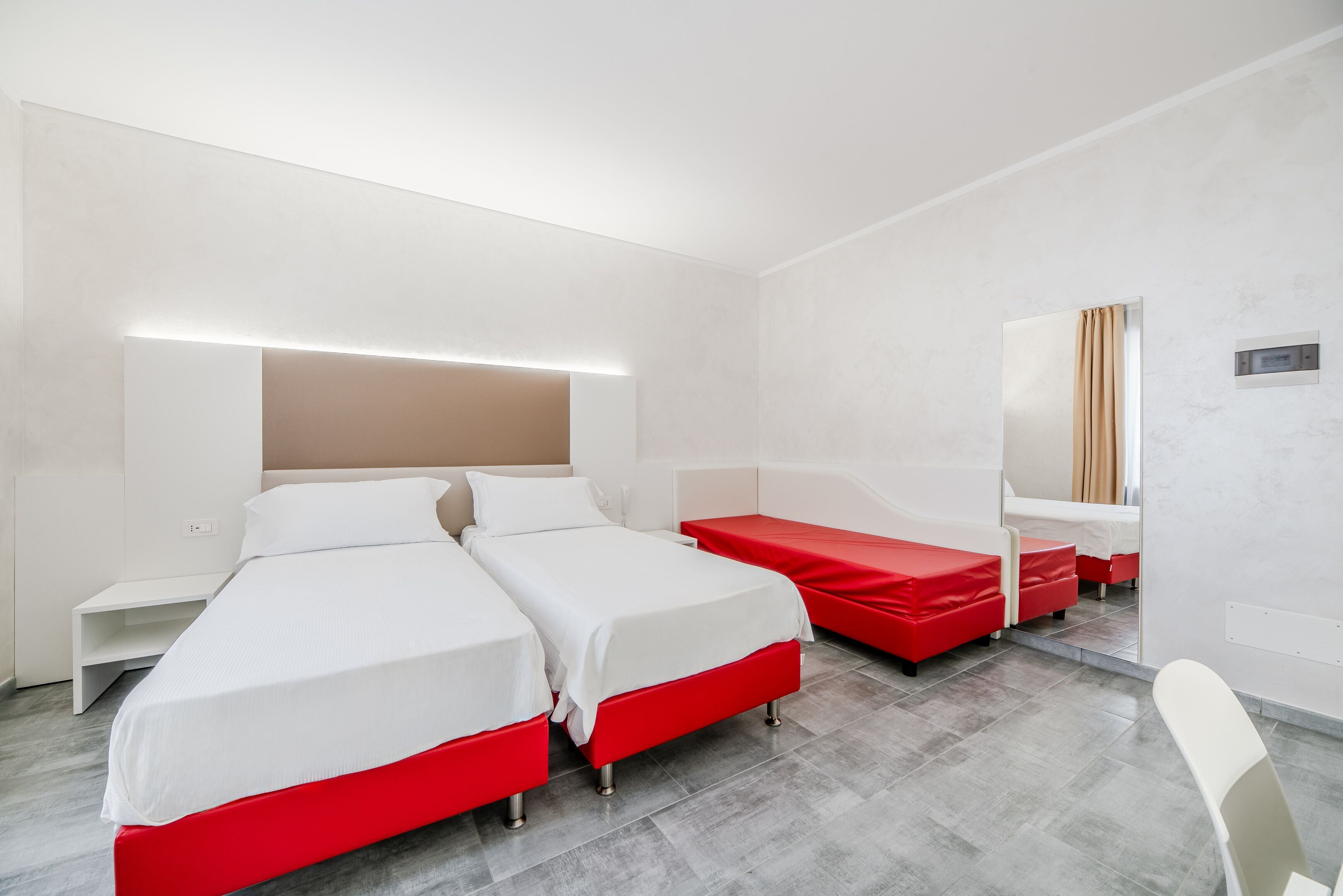 A hotel room with two beds, a desk, and a mirror.