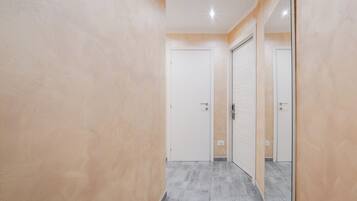 A hallway with beige walls and grey flooring, leading to a white door.