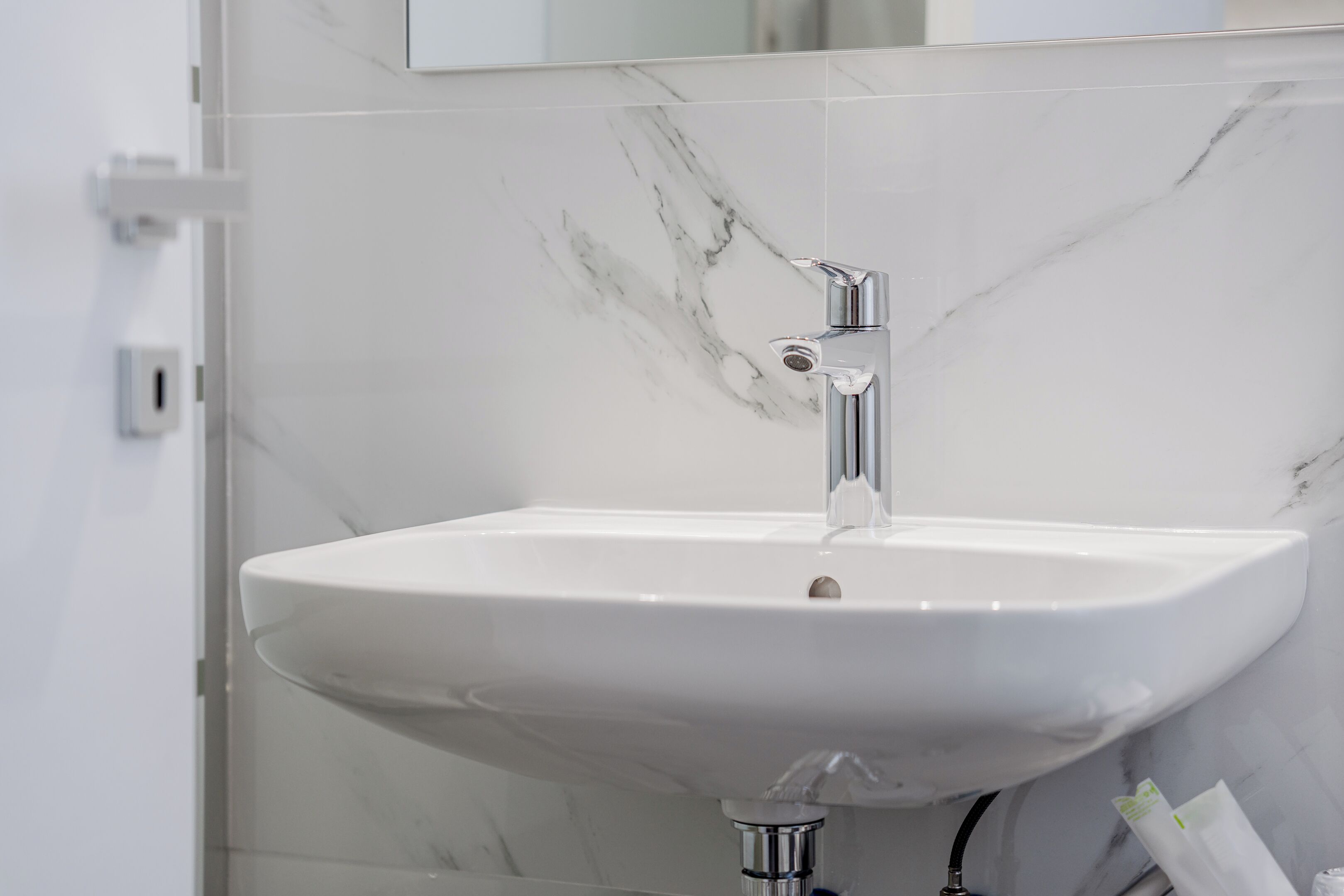 Une salle de bain avec un lavabo en marbre blanc, un robinet chromé et un miroir au-dessus.