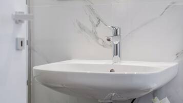 Une salle de bain avec un lavabo en marbre blanc, un robinet chromé et un miroir au-dessus.