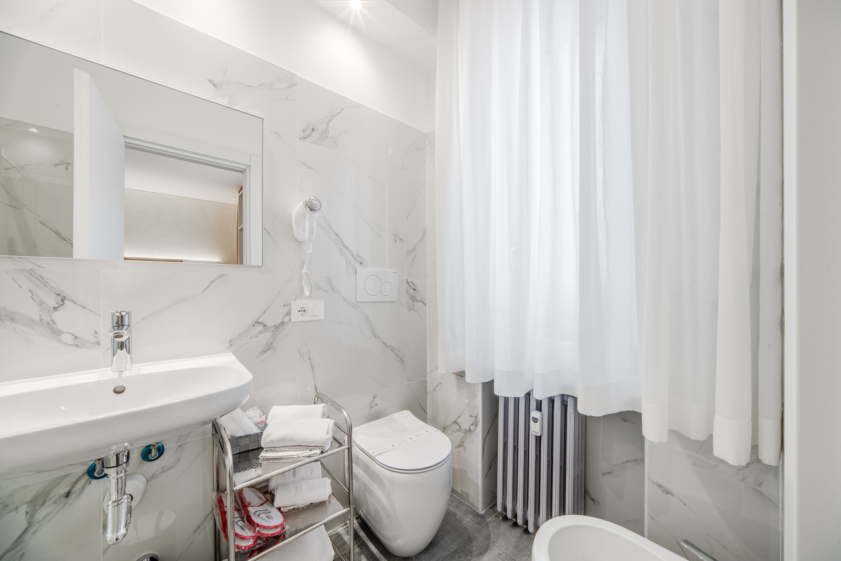 A modern bathroom with a marble sink, a toilet, and a shower area.