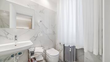 A modern bathroom with a marble sink, a toilet, and a shower area.