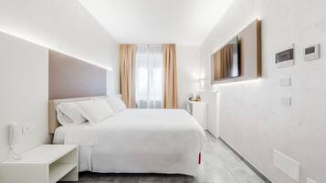 Ein modernes Hotelzimmer mit einem großen Bett, einem Nachttisch und einem an der Wand befestigten Fernseher.