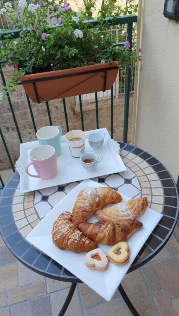 Una mesa con pasteles y tazas de café en un patio con baldosas.