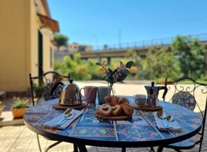 A round table with a blue patterned tablecloth, a croissant, a coffee pot, and a teapot on it. - B&B Carmelina (Gragnano)