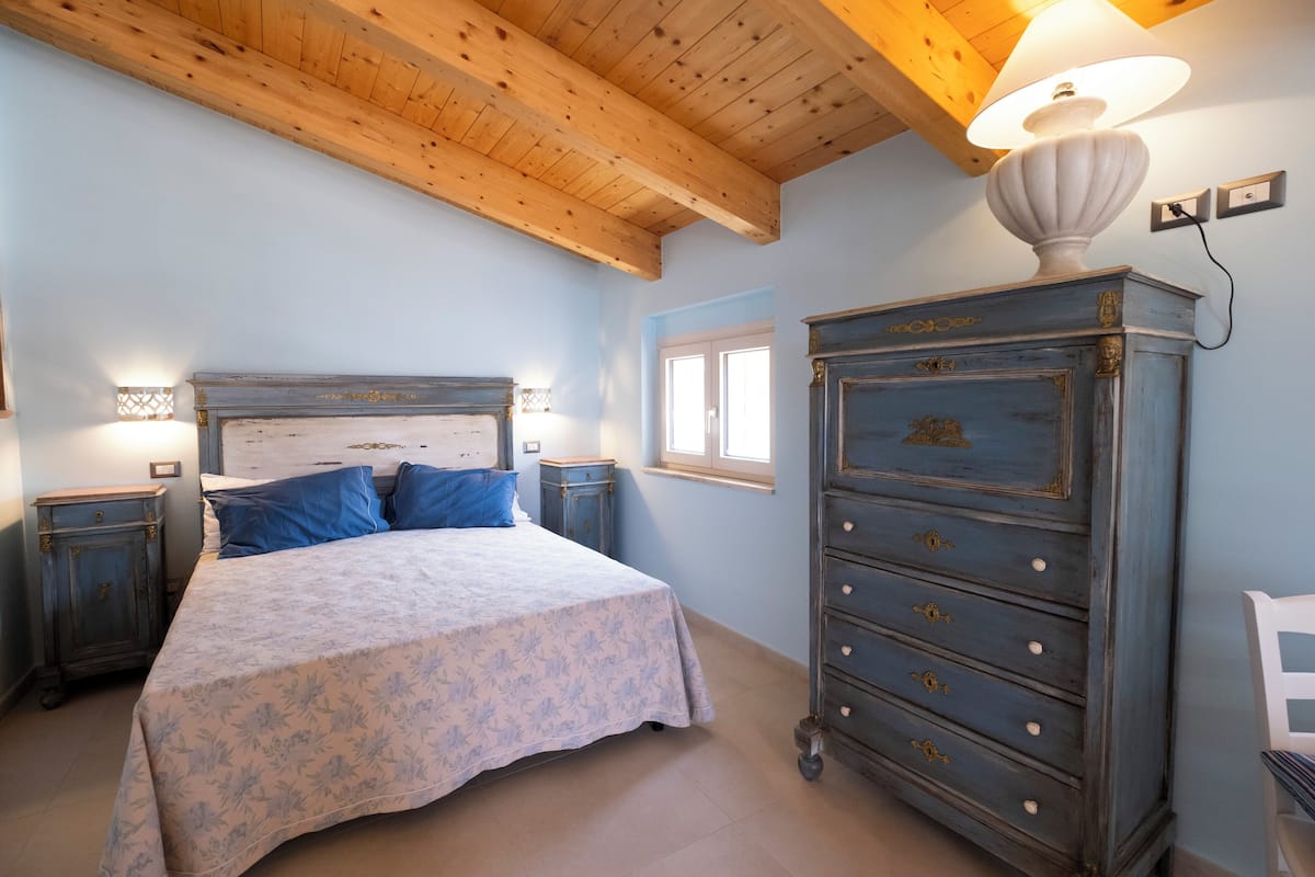 Un dormitorio con cama, mesitas de noche, cómoda y lámpara.