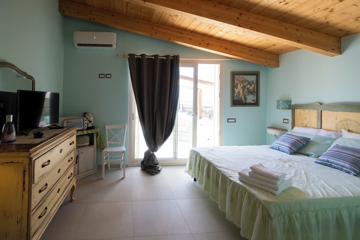Un dormitorio con cama, cómoda, silla y ventana con cortinas.