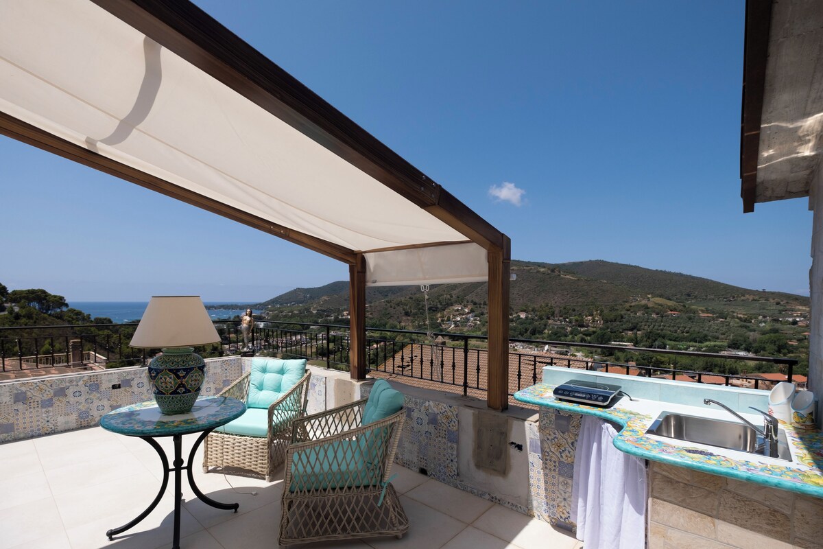 A balcony with a table, chairs, a lamp, and a sink.