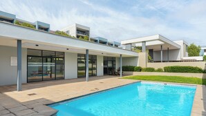 A modern building with a swimming pool, large windows, and a covered patio area. - 2 Bedroom In the Heart of Century City | Pool (Cape Town)